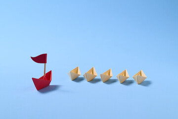 Leadership Concept with Origami Boats on Blue Background