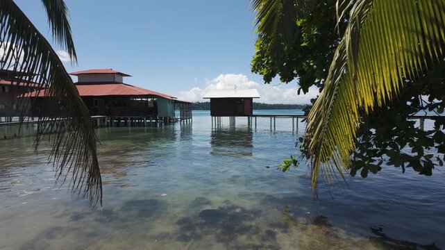 Scenic view of waterfront houses over clear, shallow water surrounded by lush vegetation on Bastimentos Island, Bocas del Toro, Panama.