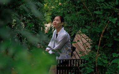 A woman sits on a garden bench.