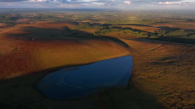 Bragan, County Monaghan, Ireland, September 2022. Drone orbits clockwise around Lough na Heery on the Irish border with Northern Ireland at golden hour with with Lough Bradan in the distance.