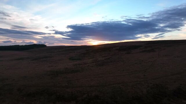 Sliabh Beagh, County Monaghan, Ireland, November 2022. Drone pushes west over the rugged peat bogs ascending to reveal the winter sunset over Eshbrack with Lough Aportan in the distance.