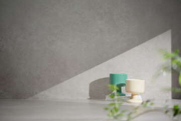 A gray-toned tile background with various props with sunlight coming through the window.