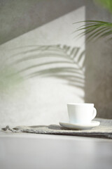 A gray-toned tile background with various props with sunlight coming through the window.