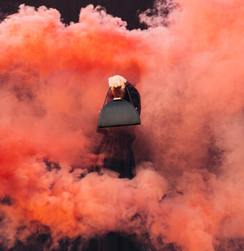 Fashionable Woman Holding Handbag Amidst Red Smoke