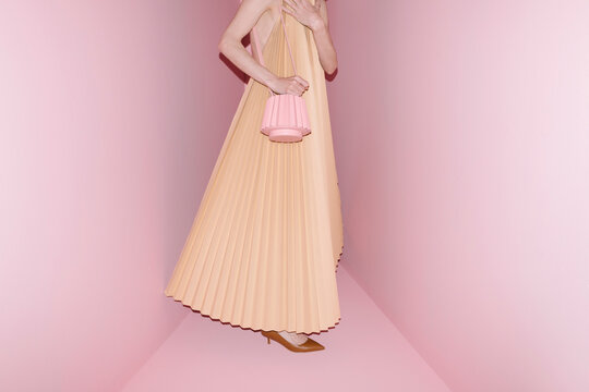 Elegant Woman in Pleated Dress Holding Handbag in Pink Room