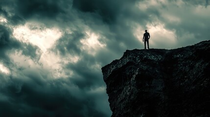 A lone figure stands atop a rocky cliff under a dramatic cloudy sky, evoking feelings of solitude and adventure.