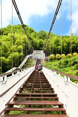 Taiwan - Jul 07, 2024: Visitors ascend and stroll on the Taiping Suspension Bridge under clear skies, surrounded by lush greenery and expansive natural beauty.