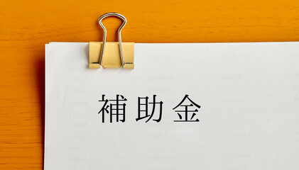 クリップで留めたたくさんの用紙に補助金の文字_俯瞰