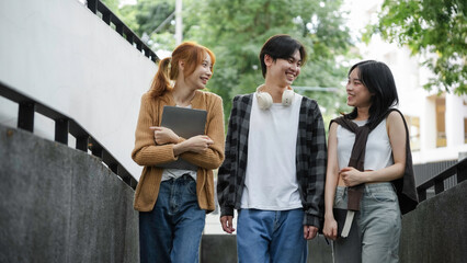 Three young students are happily chatting together while walking outside on a university campus