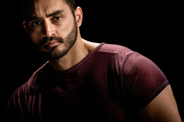 Dramatic portrait of strong brutal man with serious look, Dramatic allure: Young man's low-key portrait exudes intensity with a dark setting