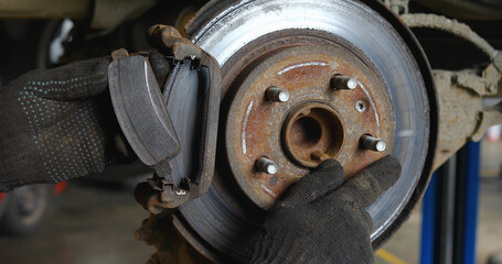 Auto mechanic shows uneven wear of the brake disc in a passenger car, the work process of...