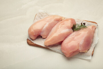 Raw chicken fillet on a cutting board on light background. Top view