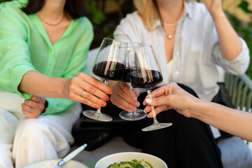 Friends having brunch, toasting, saying cheers holding wine glasses. Food and beverage celebration concept