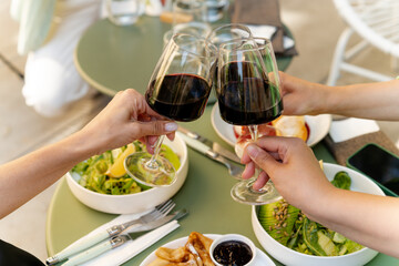 Group of friends cheers with red wine. dinner table top view