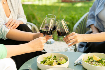 Overhead view of friends having brunch, toasting, saying cheers holding wine glasses. Food and beverage celebration concept