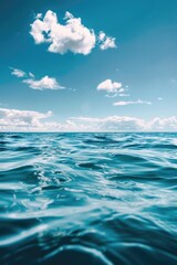 Fototapeta premium Calm ocean waters under a blue sky with puffy clouds.