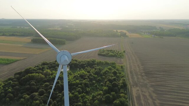 Lone wind turbine is standing in the middle of a patchwork of farm fields, generating clean energy for the surrounding countryside