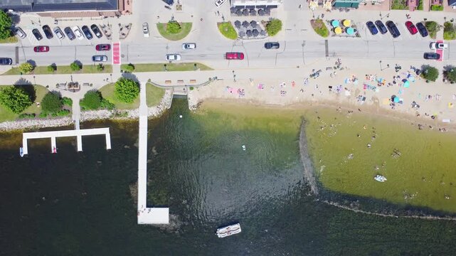 Summer Beach Activities On Pewaukee Lake, Waukesha County, Wisconsin. 4K Slow Motion Aerial PanOver The Fishing Pier And Beach Park.