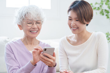 高齢者の母親にスマホを教える娘（家族・ファミリー）