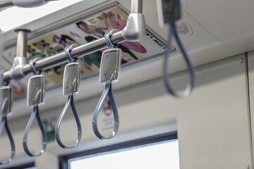 View from inside the city bus with passengers. Handles for standing passenger inside a bus. Bus hangers for people that are standing to hold on something during ride