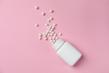 Homeopathic remedy. Overturned plastic bottle and pills on pink background, top view