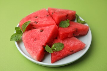 Pieces of tasty watermelon and mint on green table, closeup