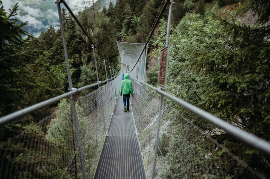 Two boys walk on a suspension bridge in rainy Wallis, Switzerland