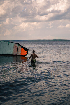 Man kitesurfer folds his kite on the water.