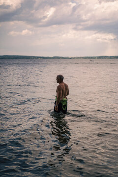 A man in a wetsuit enters the water.