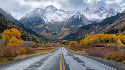 Naklejka premium Mountain Road Leading to Snowy Peaks in Autumn