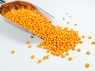 Turmeric yellow masterbatch granules in a scoop on a white background.Color pigment carrier polymer...