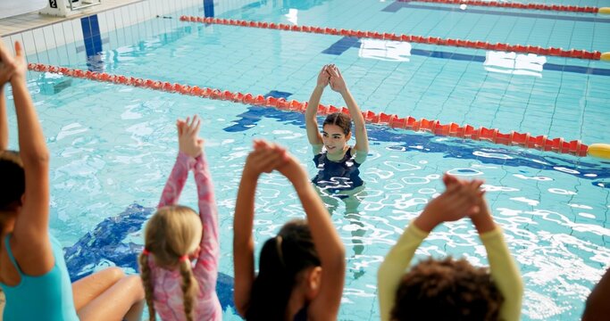 Swimming pool, woman and children with fitness, water and coach with safety, instructions and teaching. People, trainer and students with recreation, learning and instructor with conversation or kids