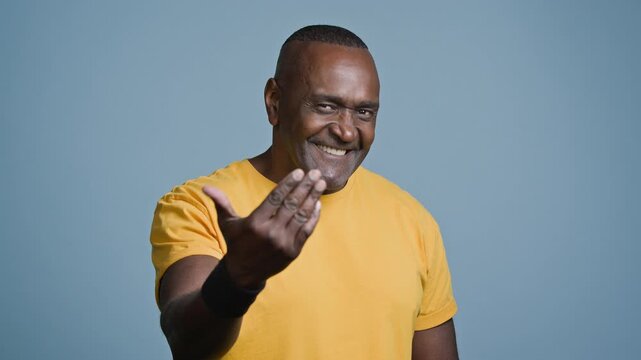 Attractive positive athletic African American man athlete personal fitness trainer advertise sports services in studio on blue background smiling looking at camera male sportsman invite to training