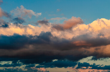 Dramatic clouds in the blue sky in the morning, the rising sun rays hitting the clouds