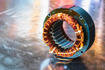 Electric motor stator with winding coil on metal surface of worshop table