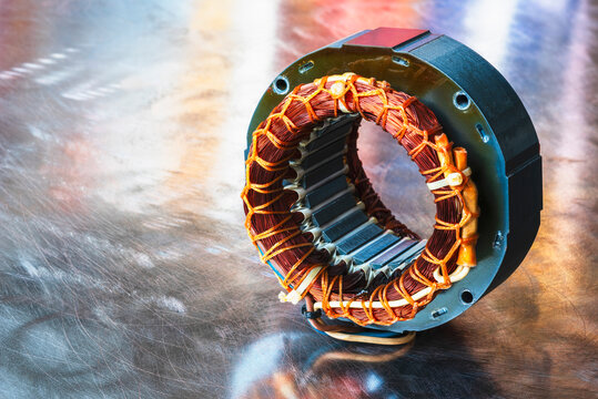 Electric motor stator with winding coil on metal surface of worshop table