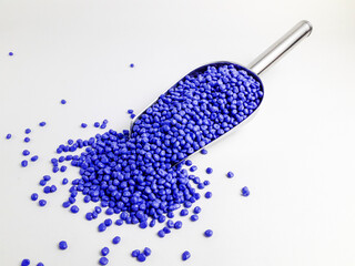 Azure blue masterbatch granules in scoop and isolated white background.Color pigment carrier...