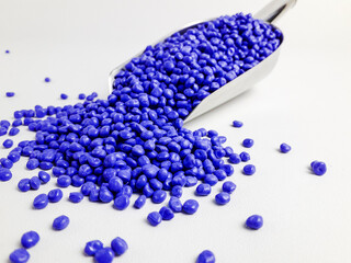 Azure blue masterbatch granules in scoop and isolated white background.Color pigment carrier...