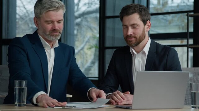 Caucasian men professional businessmen business partners coworkers discussing contract at meeting in office discuss project review paper documents report manager seller offer profitable deal to client