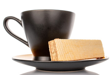 Single vanilla wafer with black ceramic cup on saucer, macro, isolated on white background.