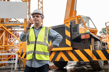 Caucasian mature engineer man worker use walkie talkie working with spare crane background	