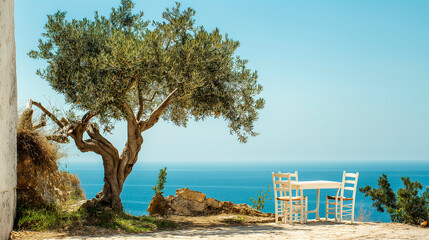 A lonely full of olives tree on a greek coast cliff, old white greek house, old white chairs and table