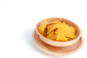 Corn chips on wooden plate isolated on white background. Crispy snack dessert. Food Photography Concept