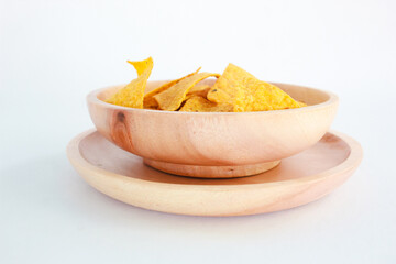 Corn chips on wooden plate isolated on white background. Crispy snack dessert. Food Photography Concept