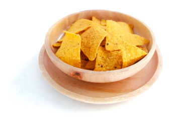 Corn chips on wooden plate isolated on white background. Crispy snack dessert. Food Photography Concept