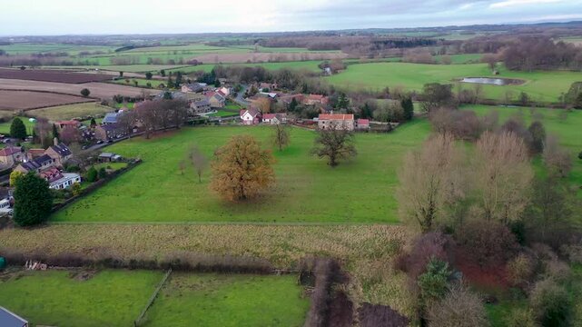 Aerial footage across the beautiful small town of Little Ribston in the Harrogate district of North Yorkshire in the UK showing a scenic view of the farmers fields in the winter time