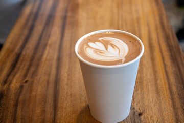 A To-Go Cappuccino in a Paper Cup on a Wood Counter