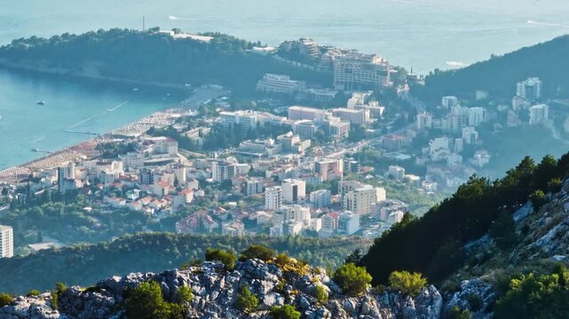 Telephoto drone shot of Bečići city from the highlands, sunny day in Montenegro