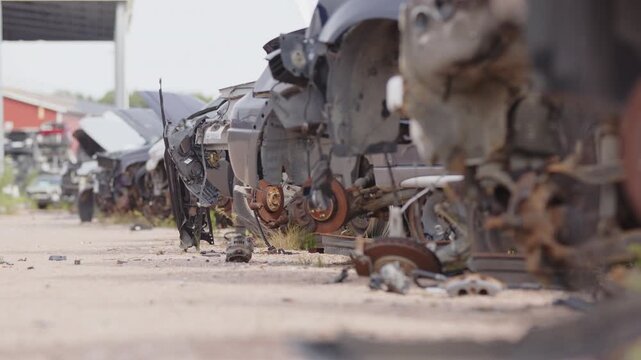 Shallow focus low angle slider of abandoned rusty vehicles at scrapyard