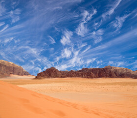 Wadi Rum Desert also known as The Valley of the Moon (against the sky with clouds)-- is a valley cut into the sandstone and granite rock in southern Jordan 60 km to the east of Aqaba